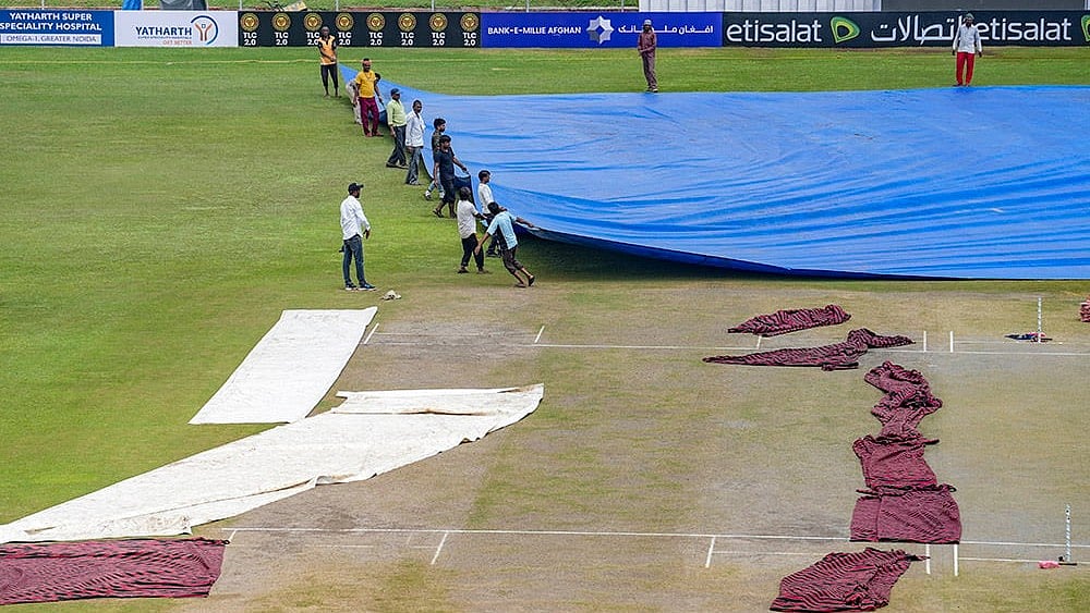 | Photo: PTI/Kamal Kishore : Afghanistan Vs New Zealand Test: Groundsmen remove the cover of the pitch before the start of second day match